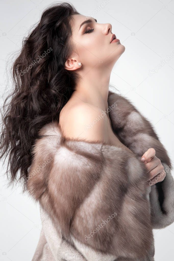 Beautiful elegant woman posing in luxury fashion fur coat over w
