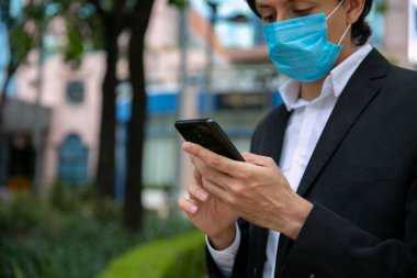 Sokakta cep telefonu kullanan adamların stok fotoğrafı. Virüsü önlemek için koruyucu bir maske takıyor. Coronavirus konsepti