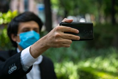 Sokakta cep telefonu kullanan adamların stok fotoğrafı. Virüsü önlemek için koruyucu bir maske takıyor. Coronavirus konsepti