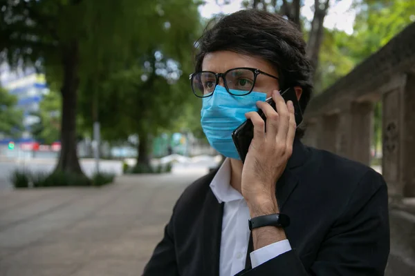 Sokakta cep telefonuyla konuşan adamların stok fotoğrafı. Virüsü önlemek için koruyucu bir maske takıyor. Coronavirus konsepti