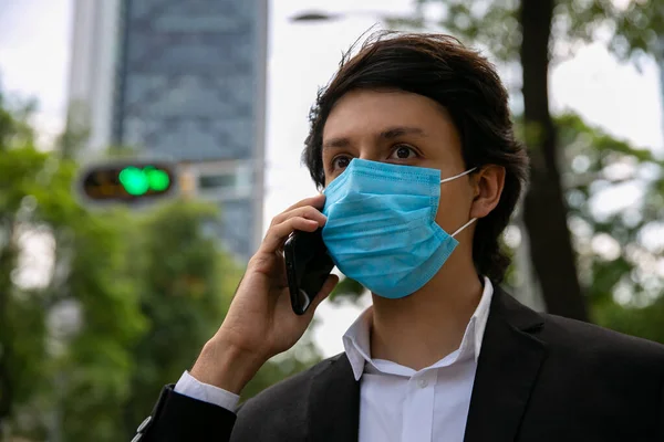 Sokakta cep telefonuyla konuşan adamların stok fotoğrafı. Virüsü önlemek için koruyucu bir maske takıyor. Coronavirus konsepti
