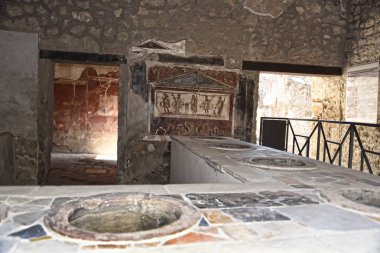 Shop counter in the once buried Roman city of Pompeii south of Naples under the shadow of Mount Vesuvius also near Naples in Italy clipart