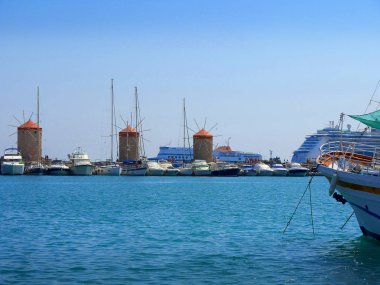 Mandraki Limanı Rodos Adası üzerinde. Bir liman duvar ve Governors Palace tarafında stand üç yel değirmenleri ve St Nikolas kale ve kilise varsayım stand diğer tarafta