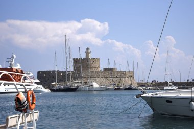 Mandraki Limanı Yunan Adası Rhodes.Three yel değirmenleri ve St Nikolas fort üzerinde durmak Harbour duvar ve Governors Palace bir tarafında ve kilise varsayım diğer stand. Derin deniz Limanı yolcu gemilerine için yakındadır