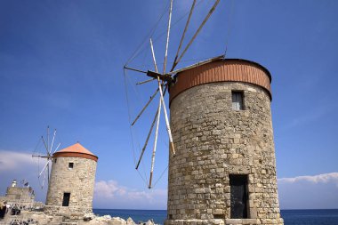 Mandraki Limanı Yunan Adası Rhodes.Three yel değirmenleri ve St Nikolas fort üzerinde durmak Harbour duvar ve Governors Palace bir tarafında ve kilise varsayım diğer stand. Derin deniz Limanı yolcu gemilerine için yakındadır