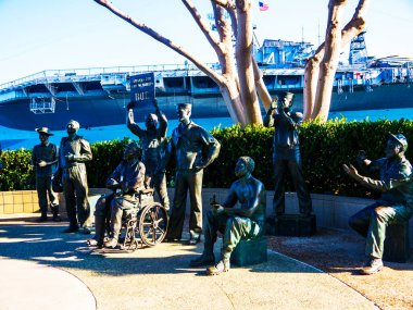 Komedyen Bob Hope 'un bronz heykeli, ABD' nin Kaliforniya 'daki San Diego Limanı' ndaki USS Midway havayolu şirketinin yanında, 2. Dünya Savaşı 'ndan bu yana her savaştan 15 erkek ve kadından oluşan Amerikan askeri kalabalığının önünde duruyor.