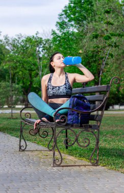 Sırt çantalı güzel esmer kız parkta bankta oturuyor ve su tabancası eğitimi alıyor. Spor anlayışı 