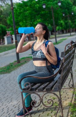 Güzel esmer kız parkta bankta oturuyor ve su perdeleri eğitimi alıyor. Spor anlayışı 