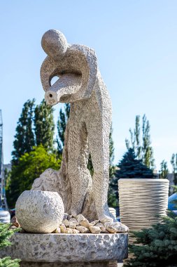 Beyaz taş heykel: bir adam sürahide su döker. Bu, suyu olmayan bir kaynaktır. Güneşli yaz günü dışarıda.