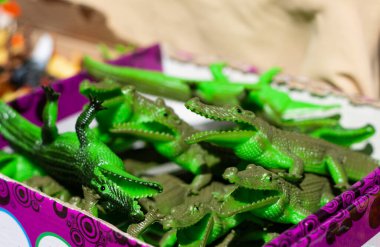Birçok küçük plastik yeşil timsah tezgahtaki hatıra kutusunda yatıyor. Güneş yazın caddede parlak bir şekilde parlar. Birçok turist hayvanat bahçesinden hayvan hediyeleri alır..