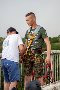 Ivanovsky Köprüsü, Ukrayna - 21 Haziran 2020: Extreme Sports kavramı. Bir eğitmen bir adamın köprüden iple atlamasına yardım eder. Tüm ekipmanlar çok sağlam ve güvenli. 