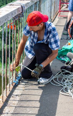 Ivanovsky Köprüsü, Ukrayna - 21 Haziran 2020: Ekstrem Spor ve Eğlence kavramı. Bir adam ipleri hazırlıyor köprüden atlamak için..  
