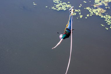 Ivanovsky Köprüsü, Ukrayna - 21 Haziran 2020: Extreme Sport kavramı. Bir kız köprüden halatla atlıyor. O, bir rüyayı gerçekleştirmekten çok mutlu. Elinde bir aksiyon kamerası var.