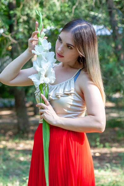 Одна Красивая Девушка Стоит Парке Белым Длинным Цветком Гладиолуса Руке — стоковое фото