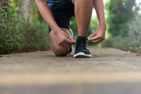 Asyalı genç fitness koşucusu Koşu ayakkabısı bağlıyor