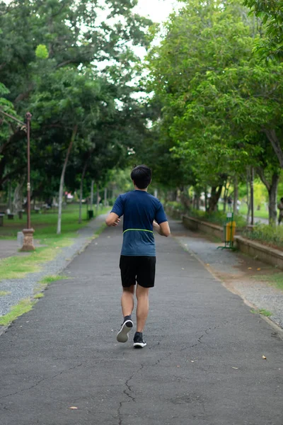 Asyalı genç fitness koşucusu parkta koşuyor.