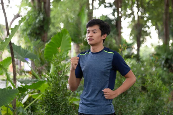 Asyalı genç fitness koşucusu parkta koşuyor.