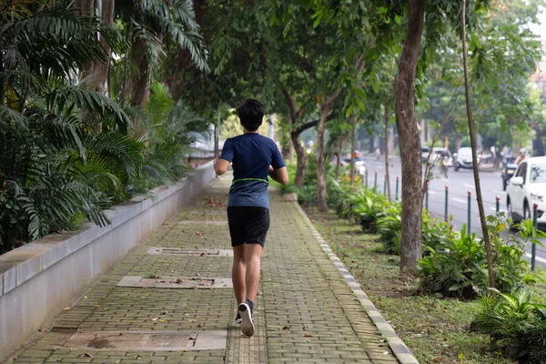 Asyalı genç fitness koşucusu parkta koşuyor.