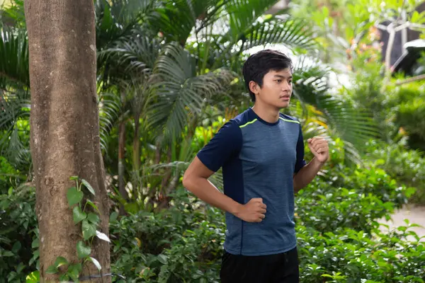 Asyalı genç fitness koşucusu parkta koşuyor.