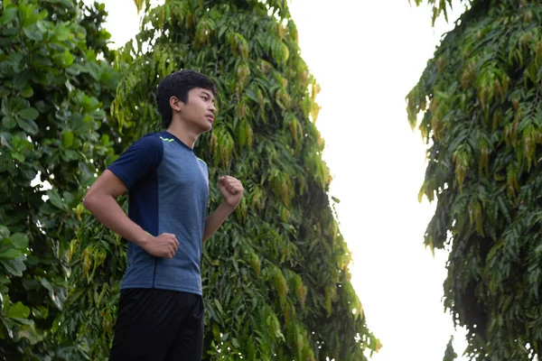 Asyalı genç fitness koşucusu parkta koşuyor.