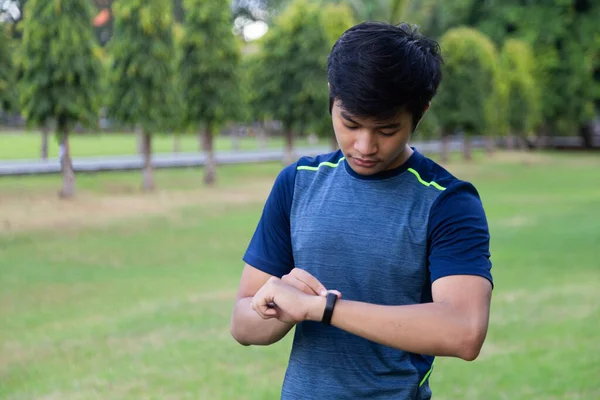 Asyalı genç fitness adamı akıllı saat bandında gelişmeleri kontrol ediyor. Çocuk koşucu akıllı saat bandı kalp atış hızı monitörüne bakıyor.