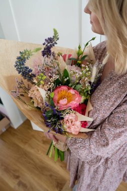 Güzel bir buket karışık çiçek kadın ellerinde taze çiçekler. Renkli çiçek buketi şakayık, gıldak çiçeği, östoma, karanfil dalı, dereotu, deniz lavantası, gerbera