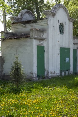 Klasik tarzda beyaz, yeşil çayırda yeşil kapıları olan eski bir bina..