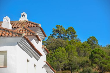 Sedir ormanlarına karşı kırmızı kil çatılı tipik bir Endülüs beyaz evinin parçası.