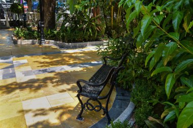 Sarı mermerli yeşil bir meydanda siyah metalden yapılmış güzel bir bank..