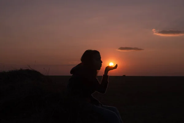 Silhouet Van Een Meisje Dat Bij Zonsondergang Haar Hand Zit — Stockfoto