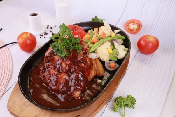 Grilled chicken with sauce on stone plate.