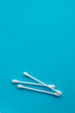 Pamuk kulak çubukları mavi arka plana yapışıyor. Kapat. Seçici odaklı görüntü, ses efekti ve tonlama. Üst Manzara. Düz yatıyordu.