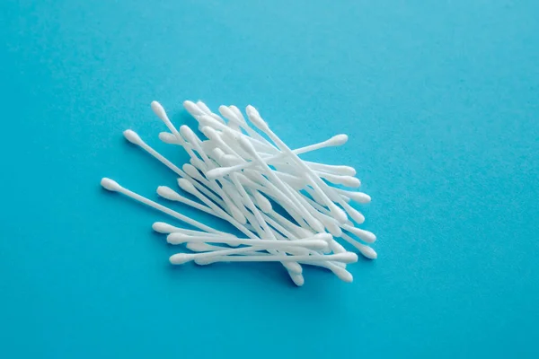 Cotton ear swabs sticks on blue background. close up. Image with selective focus, noise effect and toning. Top view. Flat lay.
