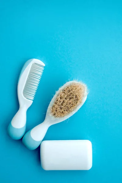 Set de accesorios para bebés para la higiene. Dos cepillos de cresta de peine de pelo blanco con mango para todo tipo de jabón blanco, aislados sobre fondo de espacio de copia azul. plano lay.Top vista. —  Fotos de Stock