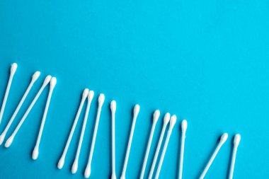 Pamuk kulak çubukları mavi arka plana yapışıyor. Kapat. Seçici odaklı görüntü, ses efekti ve tonlama. Üst Manzara. Düz yatıyordu.