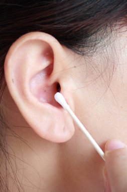 Woman cleans ears with a cotton swab clipart