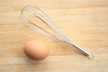 Çırpma teli ve ahşap arka plan üzerinde yumurta