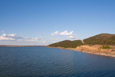 Mavi gökyüzü ve beyaz bulutlar altında göl