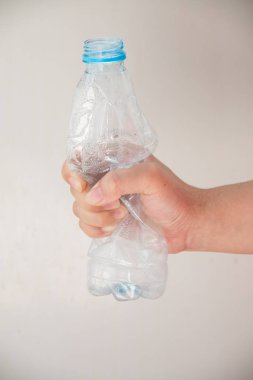 Plastik bir şişeyi elle ez.