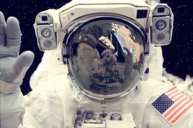 Sevimli astronot uzayda kameraya elle el sallıyor.