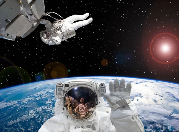 Astronauten vinka. Andra astronaut i bakgrunden. Rymd scenen. — Stockfoto