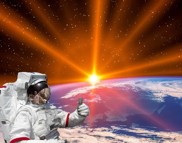 Планета Земля і захоплюючий схід сонця. Астронавт піднімає великі пальці . — стокове фото