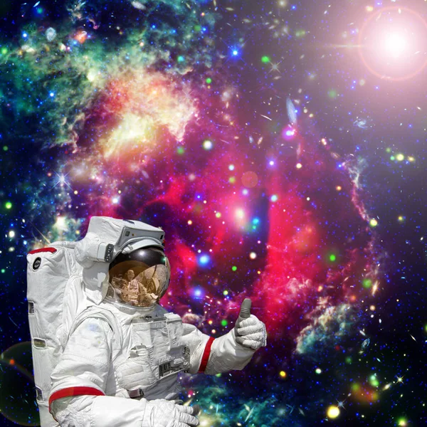 Astronauta da pulgares hacia arriba contra el espacio exterior, galaxias y estrellas — Foto de Stock