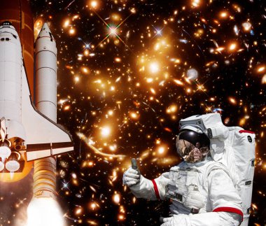 Astronot, arka planda başparmak, roket ve galaksi verir. Th