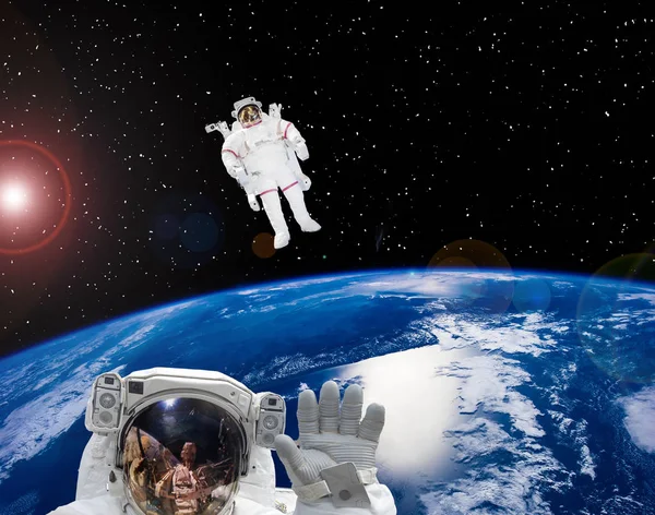Земля и астронавты в космических костюмах в космосе. Прогулка . — стоковое фото