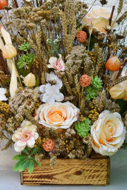 Arka plan, kurumuş bir çiçeğin dokusu. Ahşap bir kutuda bej tonlarda kurutulmuş çiçek buketi. Metin ve logo için boşluk.