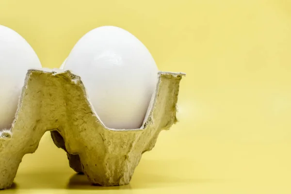 黄色の背景に段ボール箱に新鮮な白い卵 リサイクル材料で作られた持続可能な包装の鶏の卵 選択的フォーカス テキストのスペース — ストック写真