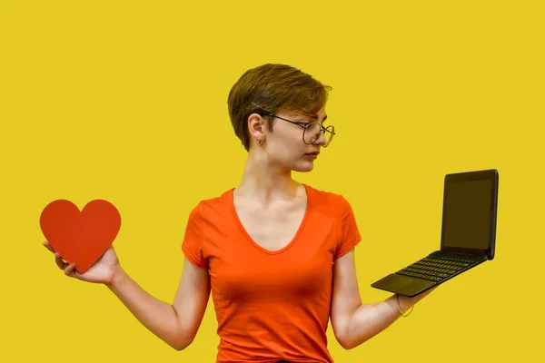 Egy Szemüveges Fiatal Választ Egyik Kezében Vörös Szívvel Másikban Laptoppal — Stock Fotó