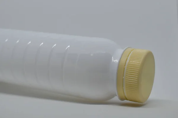 White plastic bottle with a beige cap on a gray background. Empty plastic bottle for liquids, dairy products. Plastic bottle template. Ecological problems: recycling of plastic.