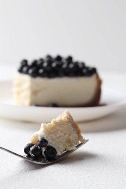 Çatalın üzerinde bir dilim cheesecake. Yabanmersinli cheesecake yakın plan.